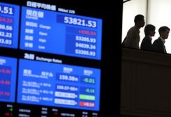 أشخاص يتجولون بالقرب من شاشات تعرض معلومات أسعار السوق في بورصة طوكيو. رويترز