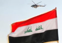 العلم العراقي يرفرف بينما تحلق مروحية في السماء خلال تدريبات في قاعدة «بسماية» العسكرية في بغداد
