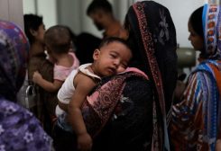 امرأة تحمل طفلا مصابا بالحصبة لتلقي العلاج في مستشفى في دكا