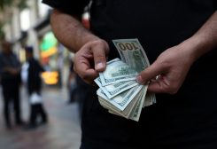 تاجر عملات يحمل أوراقا نقدية من فئة مئة دولار في طهران. رويترز
