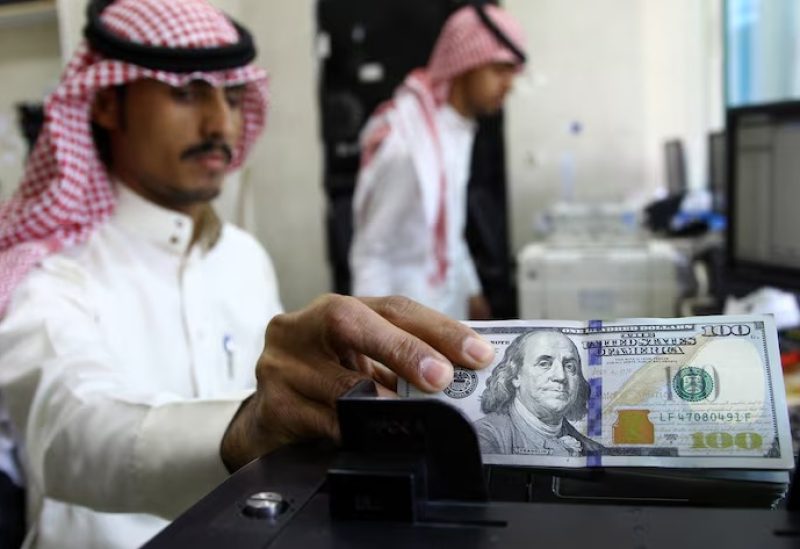 صراف يقوم بعد أوراق نقدية من عملة الدولار في محل صرف عملات بالرياض بصورة من أرشيف رويترز.